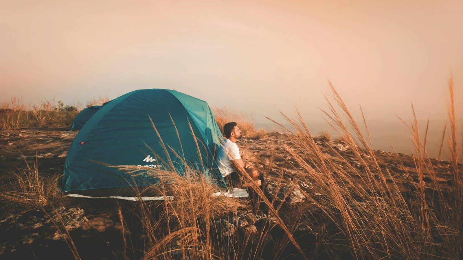 Photo of a Man Sitting Outside the Tent